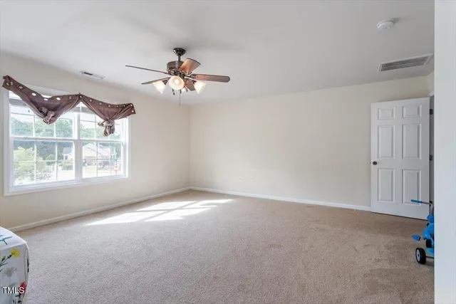an empty room with windows and fan