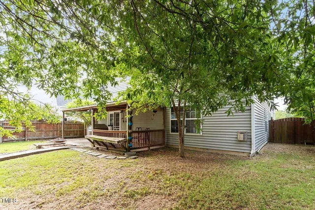 a view of a backyard with wooden fence and a large tree