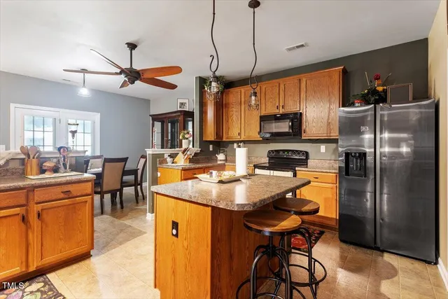 a kitchen with stainless steel appliances granite countertop a sink a stove a refrigerator cabinets and dining table with chairs