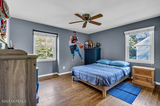 a bedroom with a bed and a dresser with wooden floor