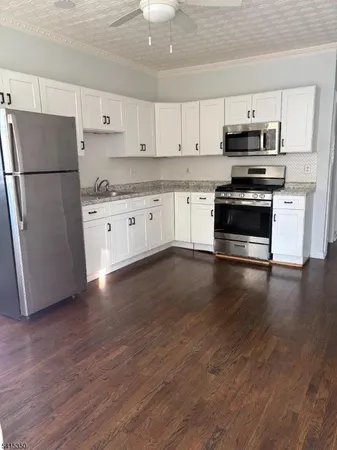 a kitchen with granite countertop a refrigerator and a stove top oven