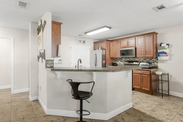 a living room with furniture a refrigerator and kitchen view