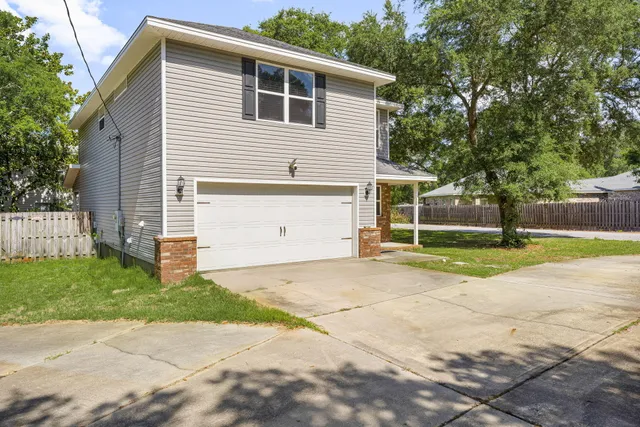 a view of a house with a yard and a large tree