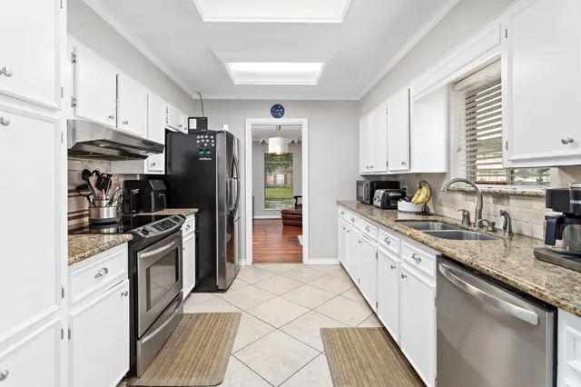 a kitchen with granite countertop a refrigerator stove and sink