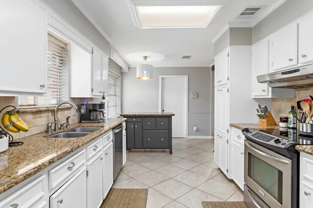 a kitchen with granite countertop a sink stove and cabinets