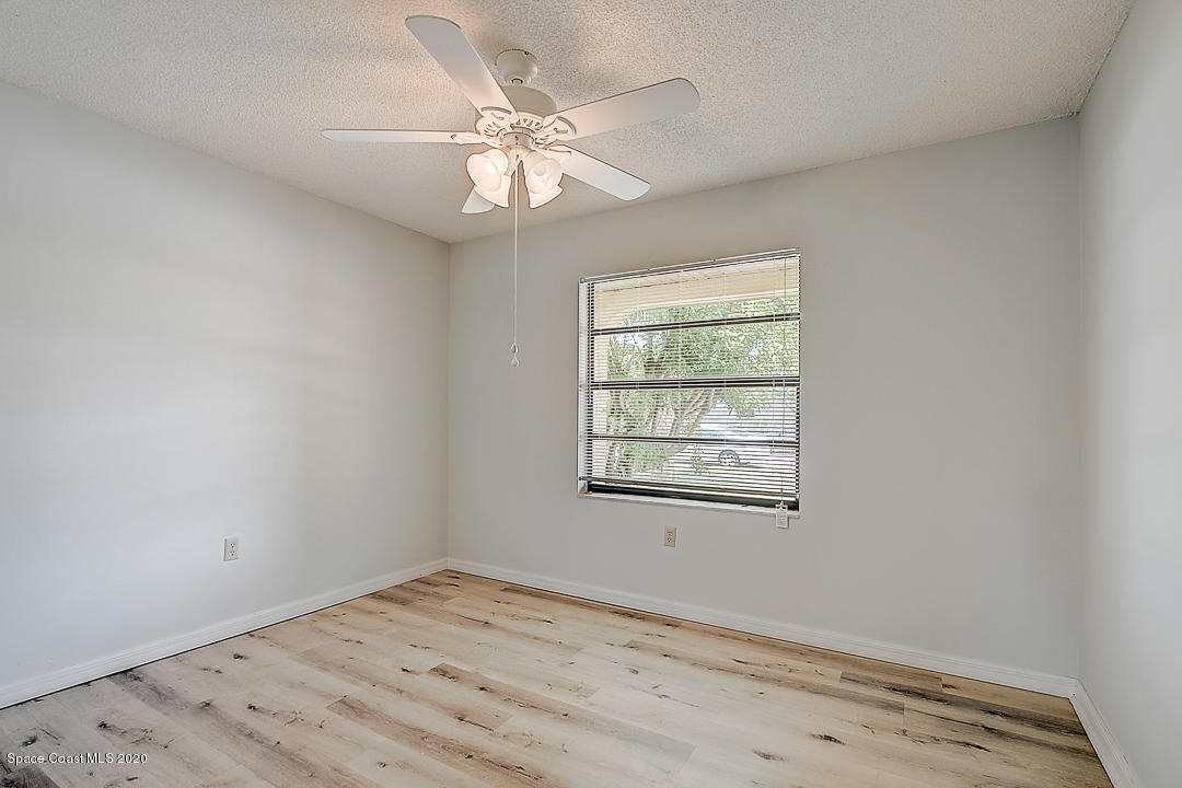 192 Cinnamon Bay Lane Melbourne, FL 32901 - Photo 22 of 34 an empty room with a chandelier fan and windows
