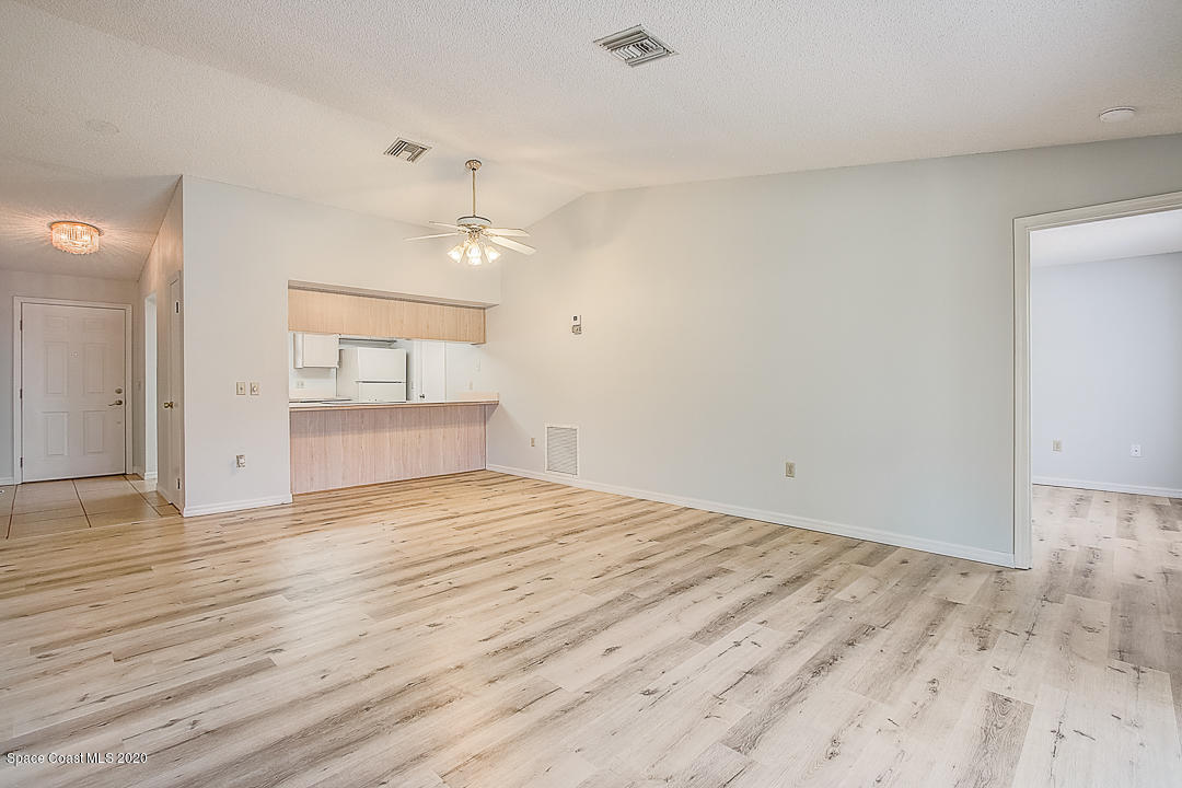 192 Cinnamon Bay Lane Melbourne, FL 32901 - Photo 8 of 34 an empty room with wooden floor chandelier and windows