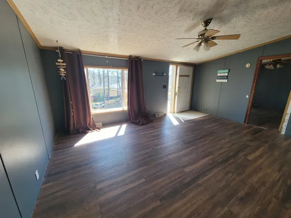 a view of an empty room with a window and wooden floor