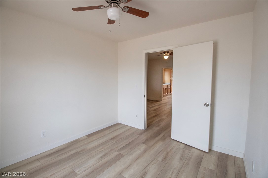 119 West Victory Road Henderson, NV 89015 - Photo 4 of 26 A well-lit bedroom features durable laminate flooring and a functional ceiling fan for comfort.
