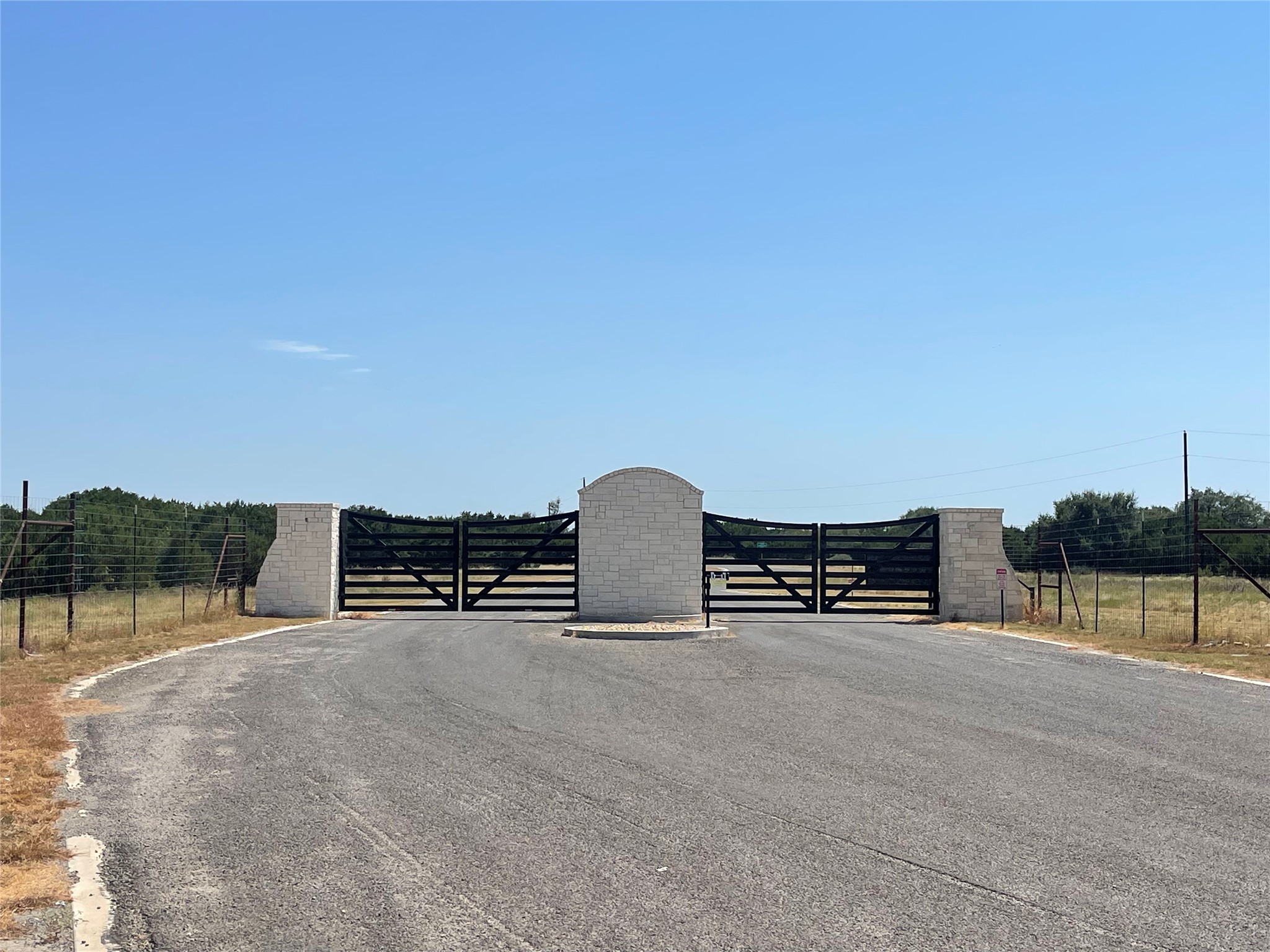 Lot 35 Cattle Trail Kempner, TX 76539 - Photo 1 of 20 Secure gated entry features stone pillars under a clear blue sky.
