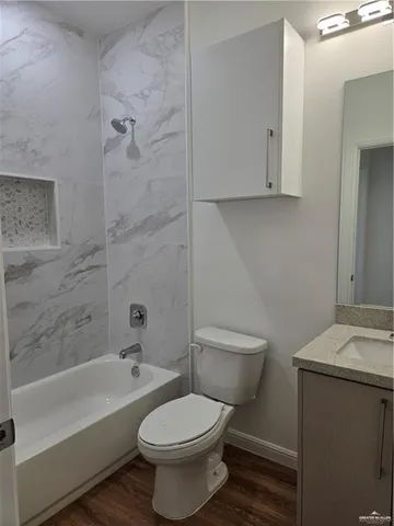 a bathroom with a toilet a sink and wooden floor