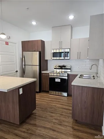 a kitchen with stainless steel appliances a sink a stove a microwave and refrigerator