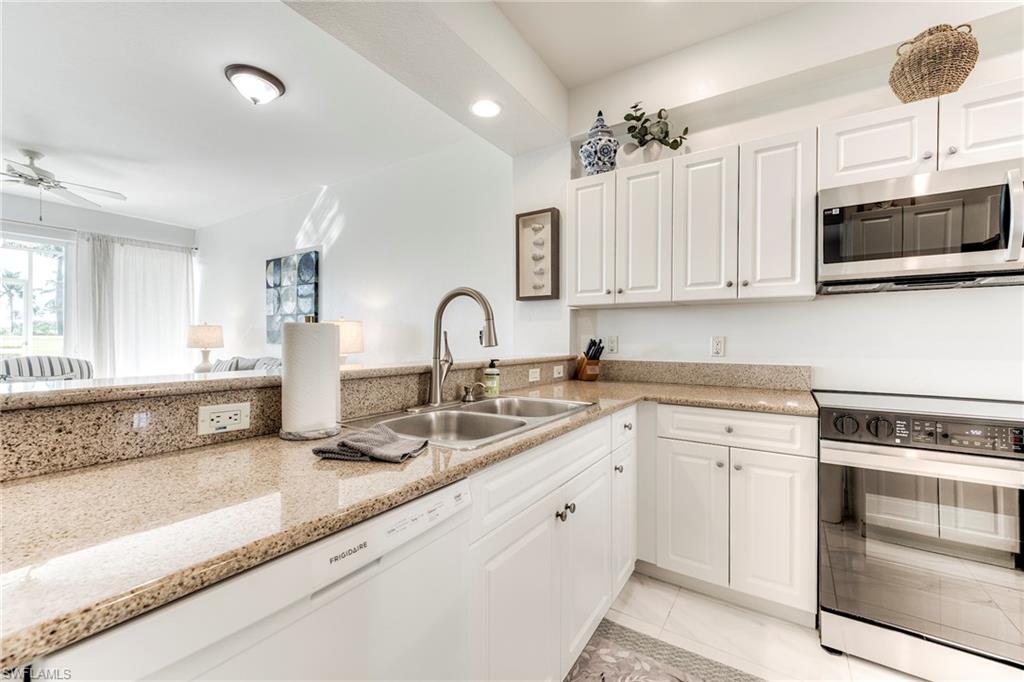 7955 Mahogany Run Lane, Unit 514 Naples, FL 34113 - Photo 13 of 30 a kitchen with stainless steel appliances granite countertop a sink a stove a microwave and cabinets