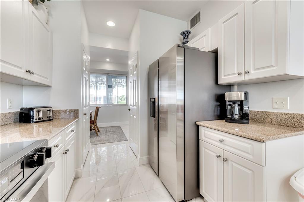 7955 Mahogany Run Lane, Unit 514 Naples, FL 34113 - Photo 14 of 30 a kitchen with kitchen island granite countertop a sink stainless steel appliances and cabinets