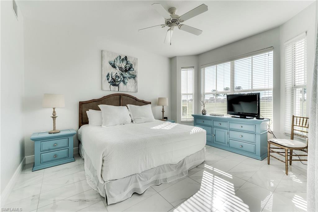 7955 Mahogany Run Lane, Unit 514 Naples, FL 34113 - Photo 19 of 30 a bedroom with a large bed and a flat screen tv