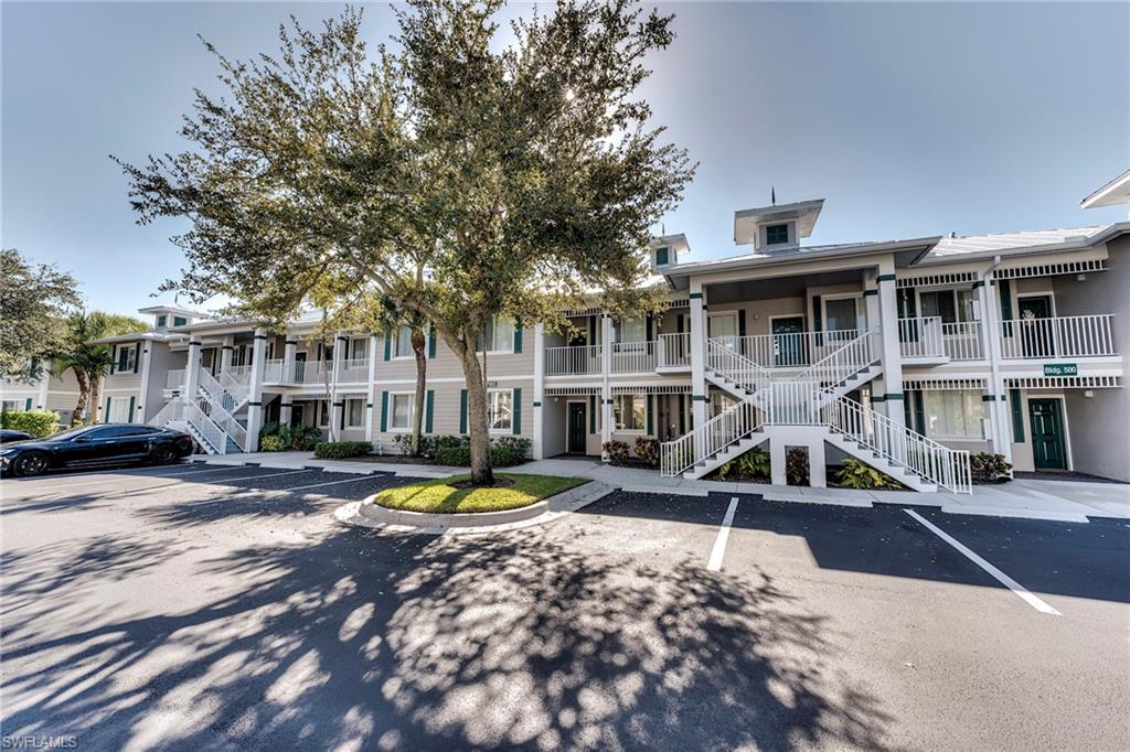 7955 Mahogany Run Lane, Unit 514 Naples, FL 34113 - Photo 2 of 30 a view of a building with sitting area and large trees