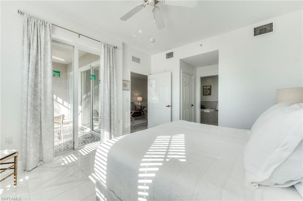 7955 Mahogany Run Lane, Unit 514 Naples, FL 34113 - Photo 22 of 30 a bedroom with a large bed and a chandelier