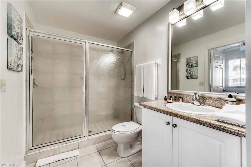 7955 Mahogany Run Lane, Unit 514 Naples, FL 34113 - Photo 29 of 30 a bathroom with a granite countertop sink toilet a mirror and shower