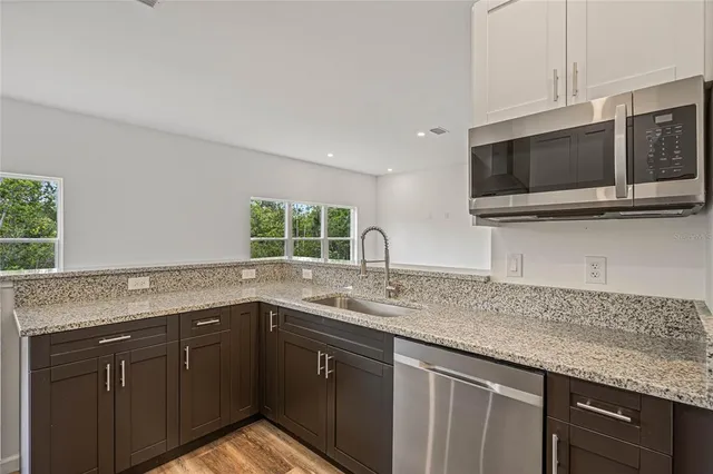 a kitchen with stainless steel appliances granite countertop a sink and a microwave