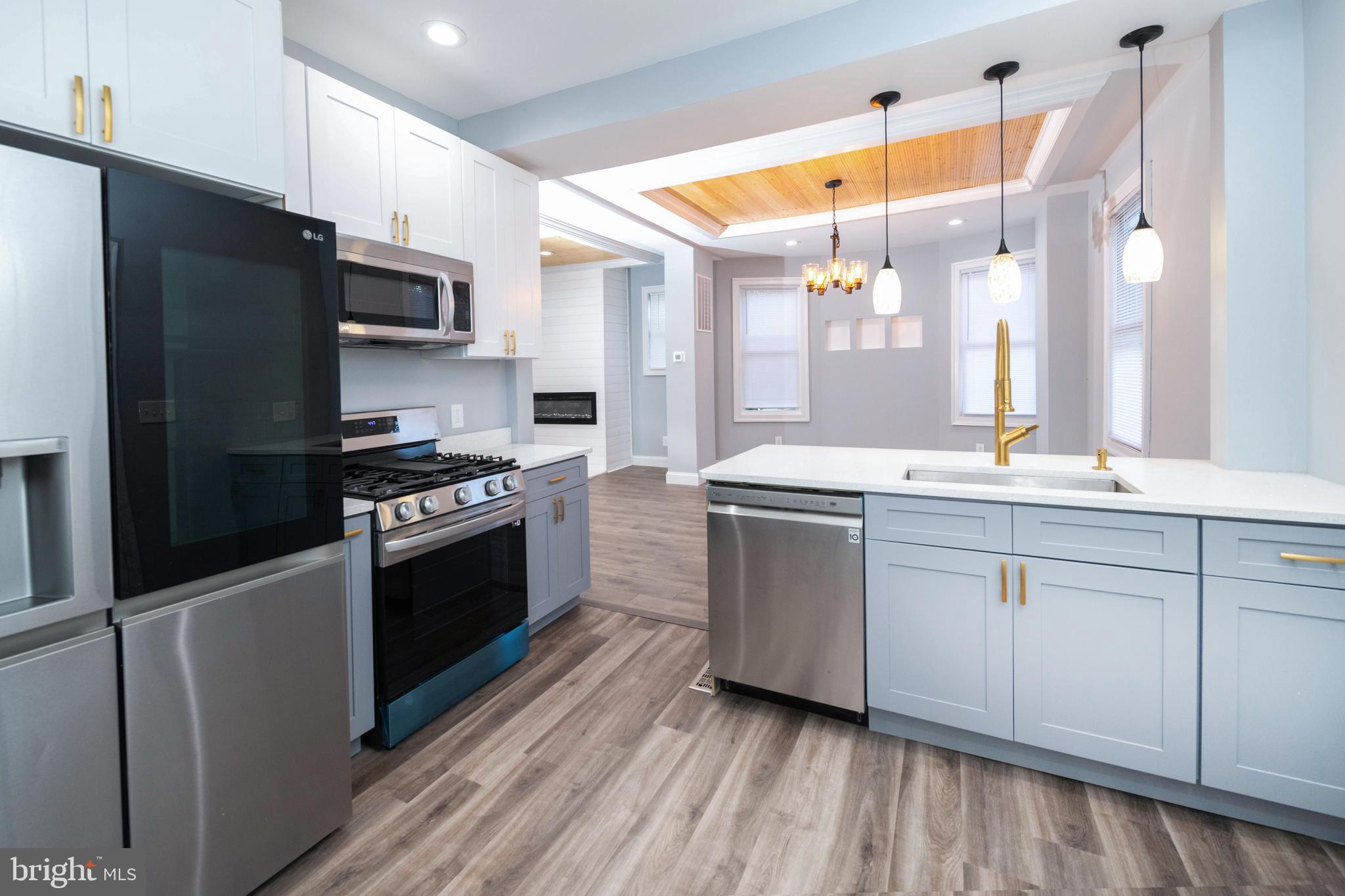 a kitchen with stainless steel appliances a sink cabinets and a wooden floor