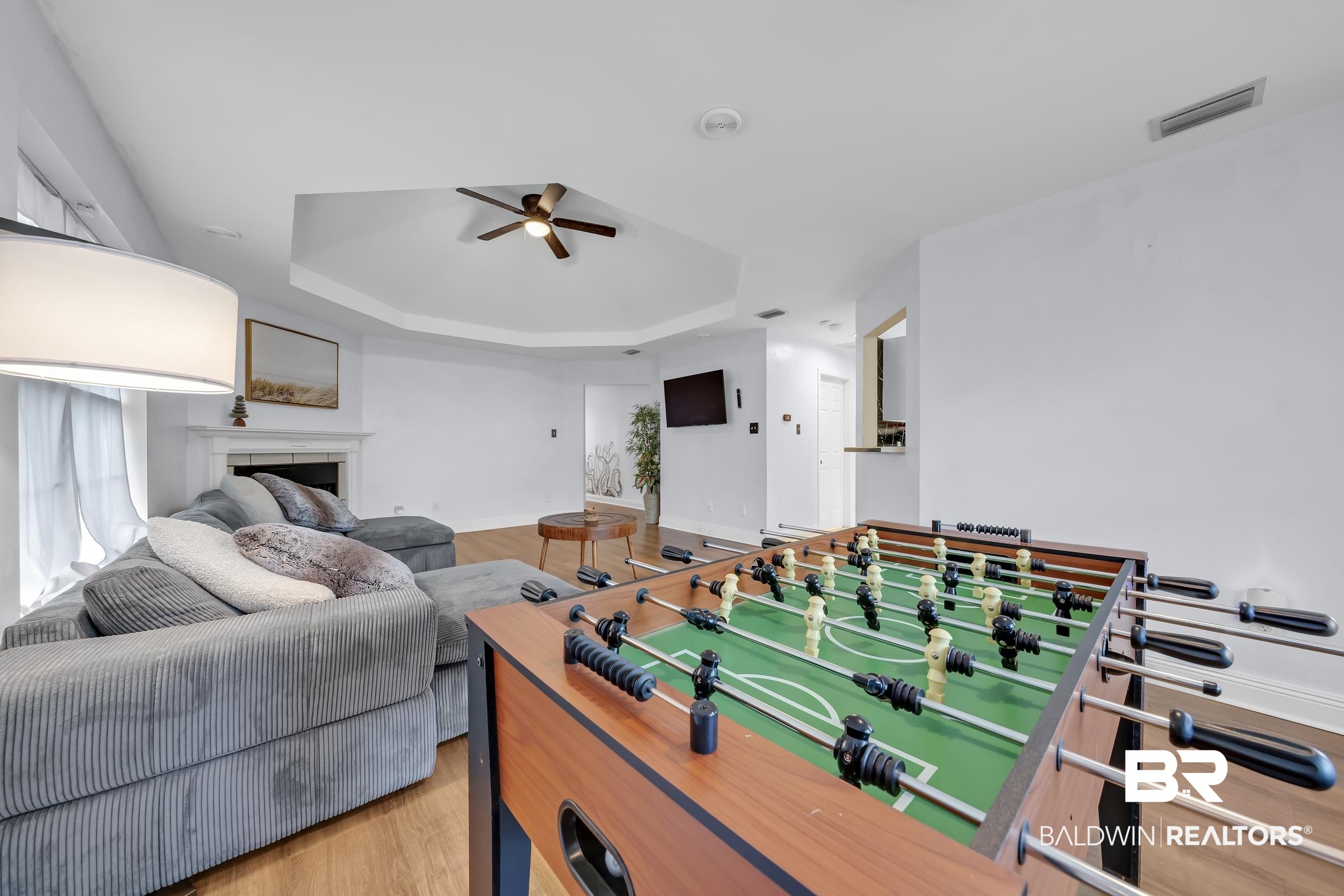 509 Loblolly Court Foley, AL 36535 - Photo 6 of 26 Spacious living area featuring light wood-finish flooring, a tray ceiling with a ceiling fan, and a fireplace with a mantel
