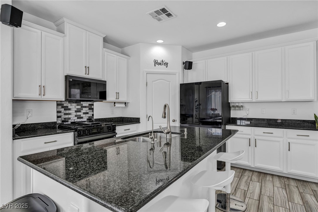854 Earth Luster Road Las Vegas, NV 89178 - Photo 24 of 65 Kitchen with visible vents, fridge, black range with gas stovetop, and white cabinets