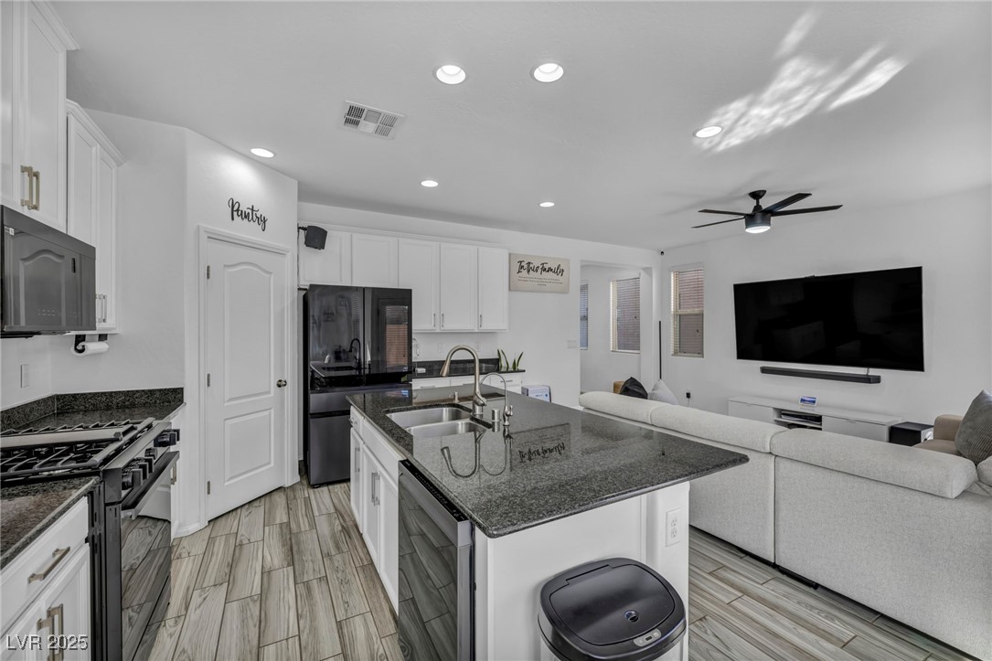 854 Earth Luster Road Las Vegas, NV 89178 - Photo 25 of 65 Kitchen featuring a center island with sink, visible vents, black appliances, white cabinetry, and a sink