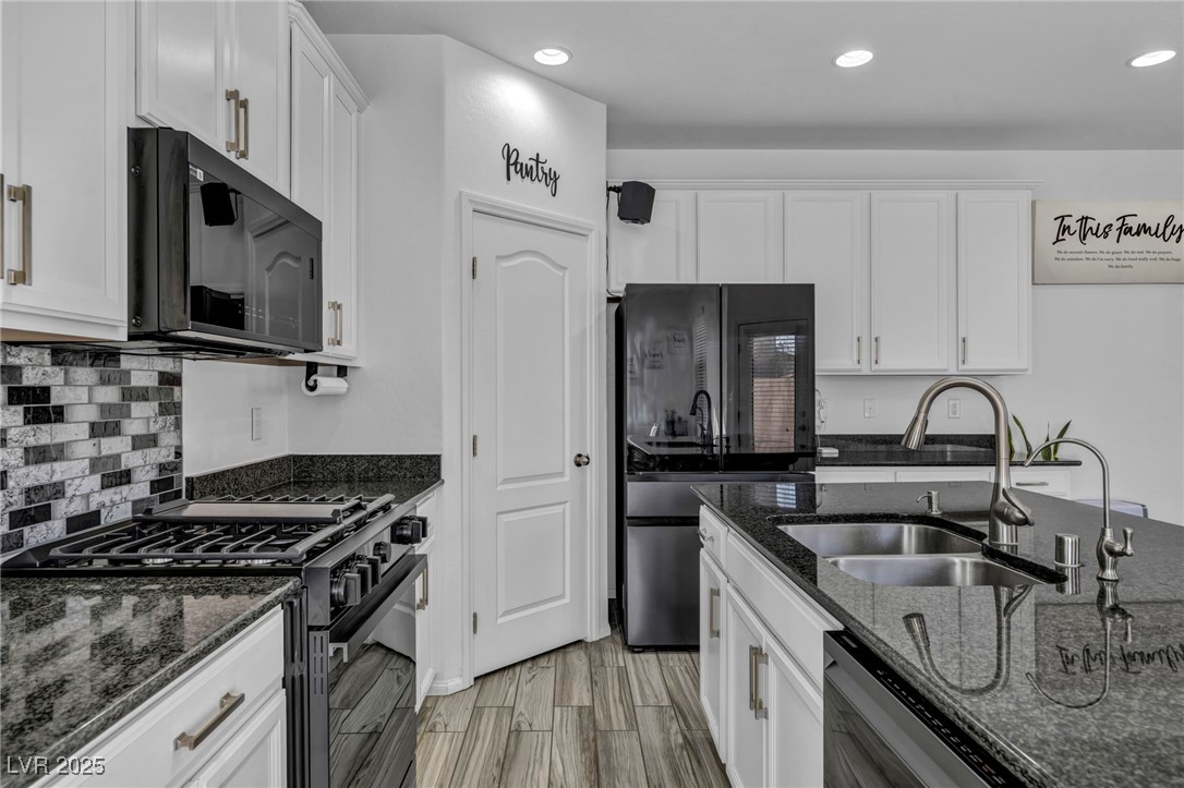 854 Earth Luster Road Las Vegas, NV 89178 - Photo 26 of 65 Kitchen featuring dark stone counters, black appliances, a sink, and white cabinets