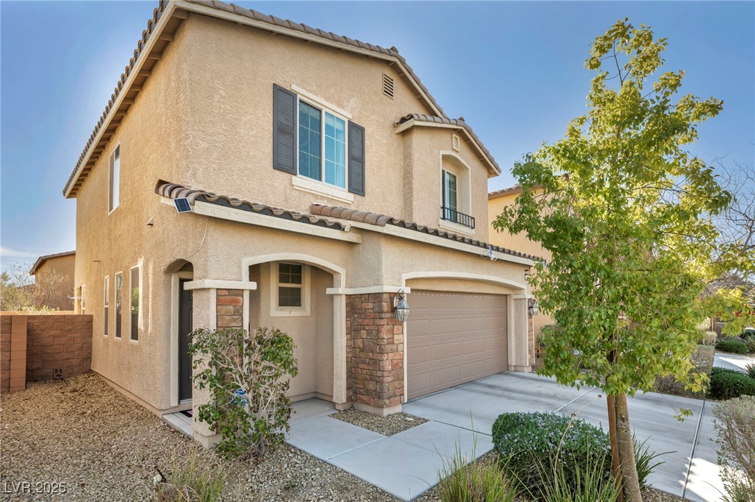 854 Earth Luster Road Las Vegas, NV 89178 - Photo 4 of 65 Mediterranean / spanish home featuring stone siding, a tile roof, concrete driveway, and stucco siding