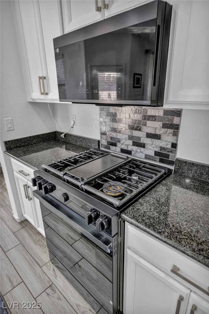 854 Earth Luster Road Las Vegas, NV 89178 - Photo 58 of 65 Kitchen featuring white cabinets, dark stone counters, range with two ovens, and decorative backsplash