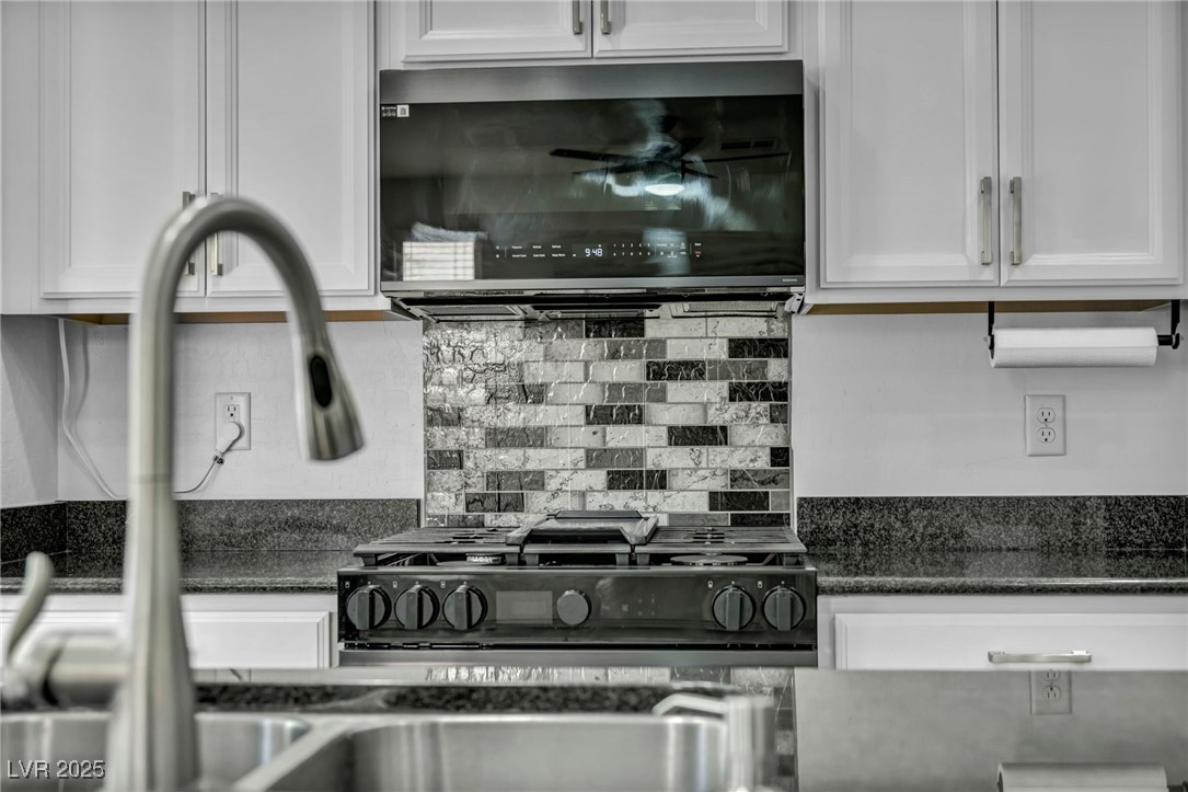 854 Earth Luster Road Las Vegas, NV 89178 - Photo 60 of 65 Kitchen featuring stainless steel microwave, white cabinetry, and decorative backsplash