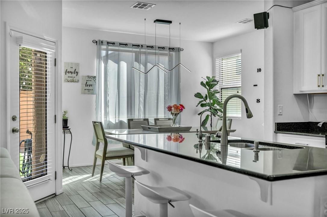 854 Earth Luster Road Las Vegas, NV 89178 - Photo 61 of 65 Kitchen featuring white cabinetry, a sink, visible vents, and a kitchen bar