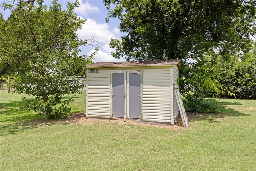 4210 Waples Road Granbury, TX 76049 - Photo 8 of 37 Storage shed featuring light-colored siding, dual panel doors, and a shingled roof