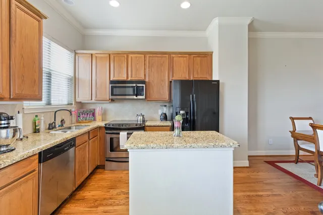 a kitchen with stainless steel appliances granite countertop a refrigerator sink and wooden cabinets