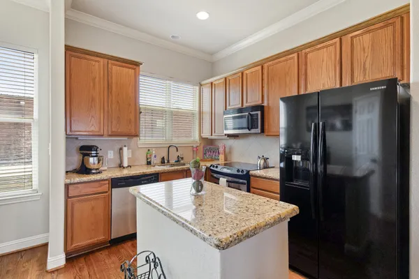 a kitchen with a granite countertop sink refrigerator and cabinets