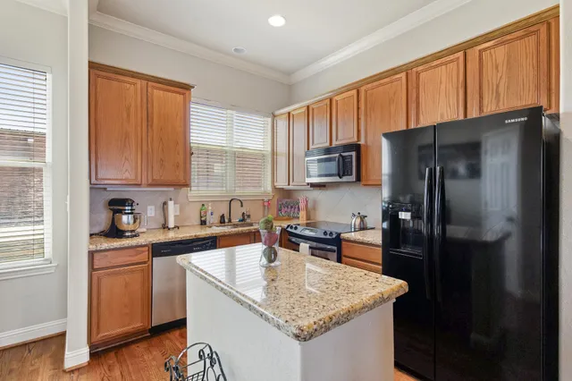 a kitchen with a granite countertop sink refrigerator and cabinets