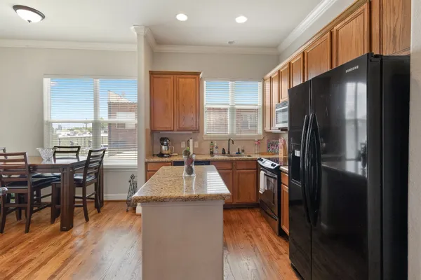 a kitchen with a refrigerator a stove a dining table and chairs with wooden floor