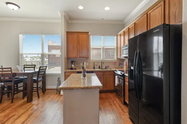 a kitchen with a refrigerator a stove a dining table and chairs with wooden floor