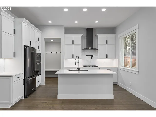 a kitchen with kitchen island stainless steel appliances a sink and a refrigerator