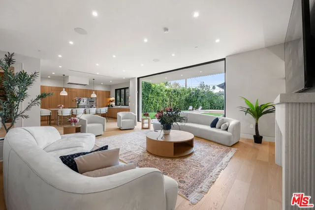 a view of kitchen with stainless steel appliances wooden floor and living room view
