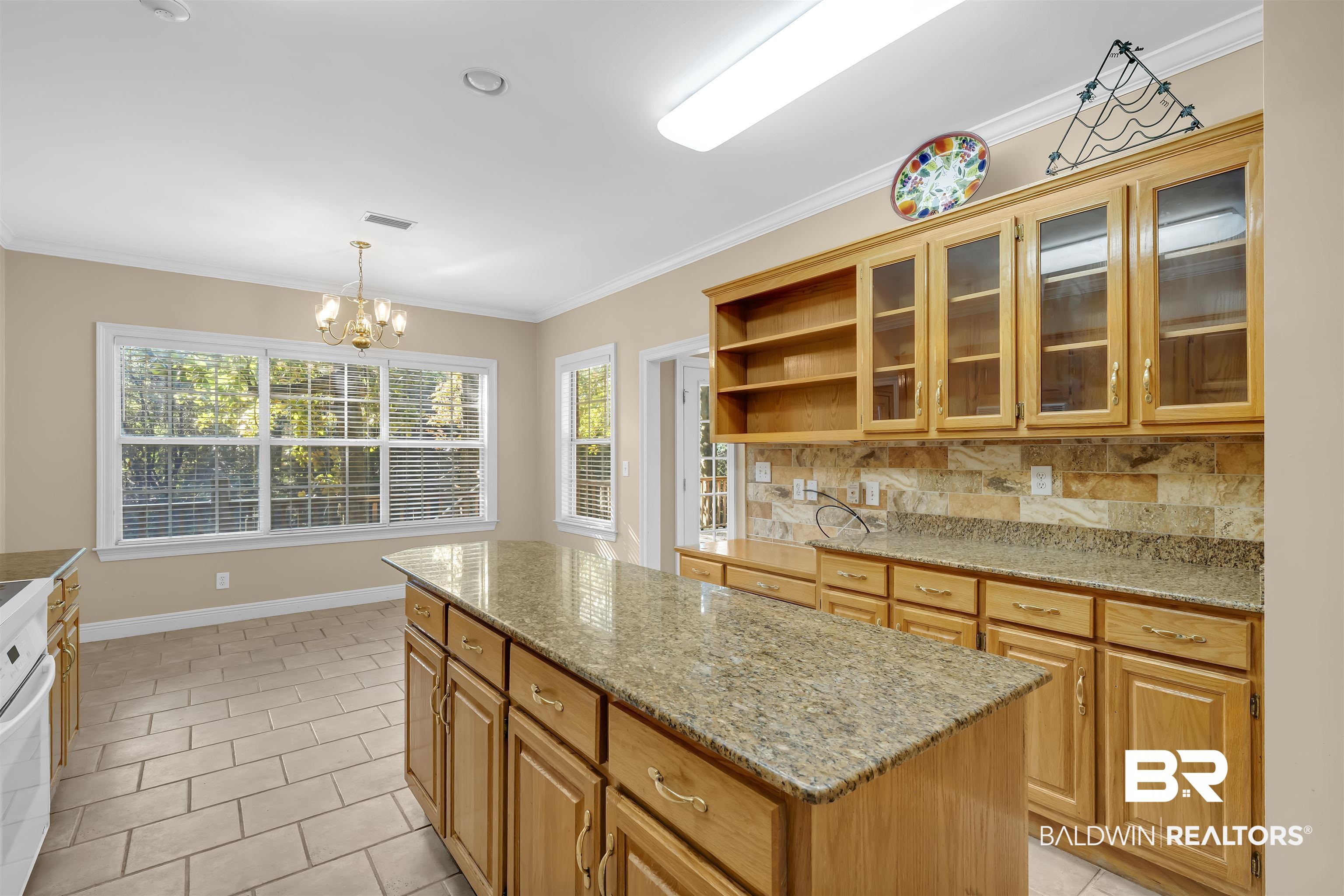 1262 Patrick Street Daphne, AL 36526 - Photo 12 of 35 Kitchen with light stone counters, glass insert cabinets, open shelves, crown molding, and decorative light fixtures