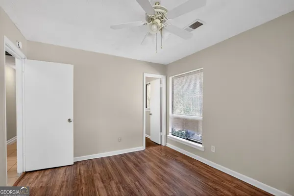 a view of an empty room with a window and wooden floor