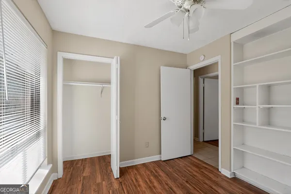 a view of empty room with wooden floor and fan