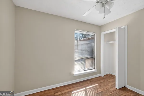 a view of an empty room with wooden floor and a window