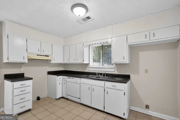 a kitchen with white cabinets and sink