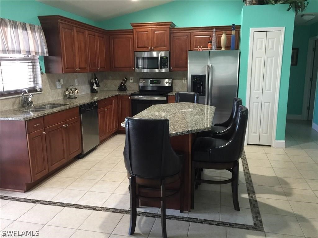239 Rue Labonne Road Fort Myers, FL 33913 - Photo 11 of 22 a kitchen with stainless steel appliances granite countertop a sink counter space and a refrigerator