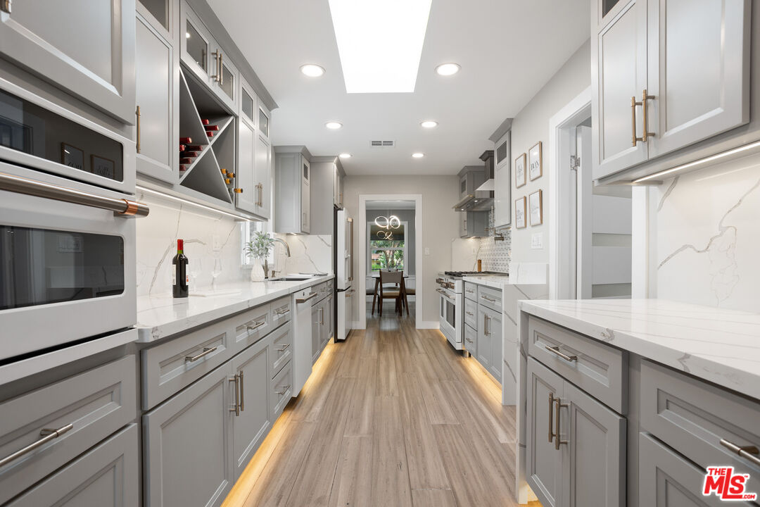 393 Allendale Road Pasadena, CA 91106 - Photo 16 of 75 a large kitchen with stainless steel appliances lots of counter space and wooden floor