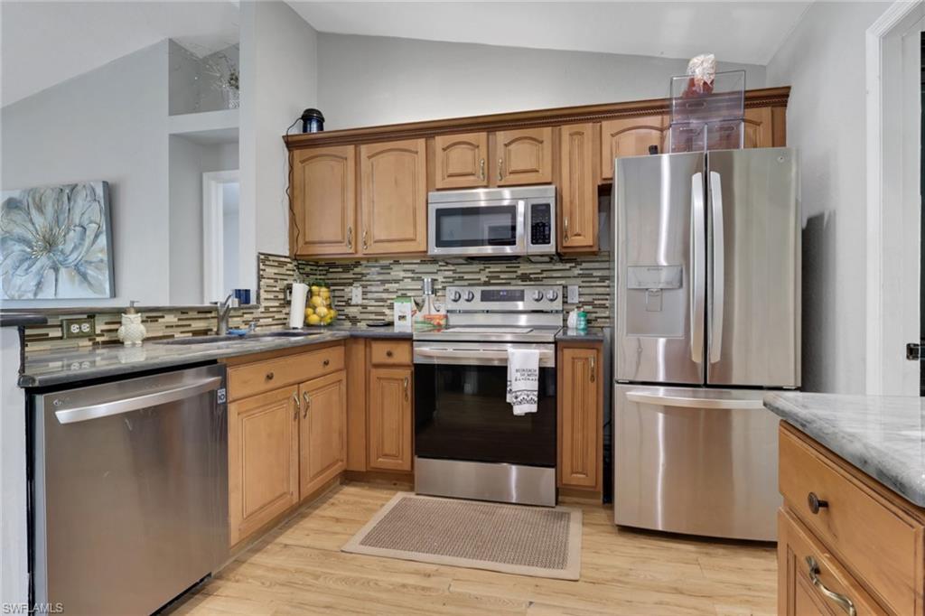 3341 2nd Avenue Southeast Naples, FL 34117 - Photo 13 of 43 a kitchen with granite countertop a refrigerator stove and oven