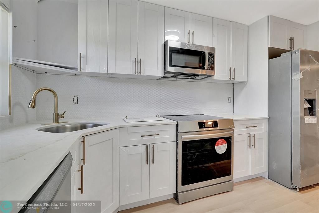 161 Northeast 10th Avenue, Unit 14A Hallandale Beach, FL 33009 - Photo 20 of 45 a kitchen with stainless steel appliances granite countertop a sink a stove a microwave and refrigerator