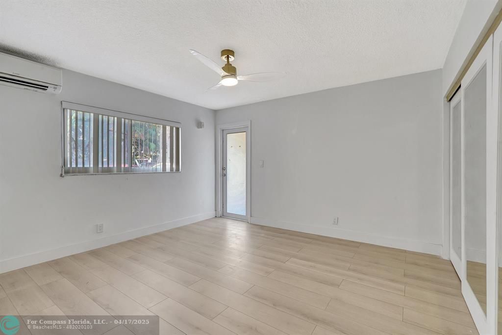 161 Northeast 10th Avenue, Unit 14A Hallandale Beach, FL 33009 - Photo 7 of 45 a view of an empty room with wooden floor and a window